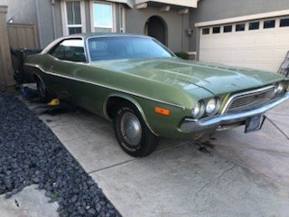 Green 1970 Dodge Challenger parked beside a house
