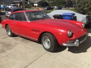 Red vintage Italian V12 grand touring coupe parked on a street