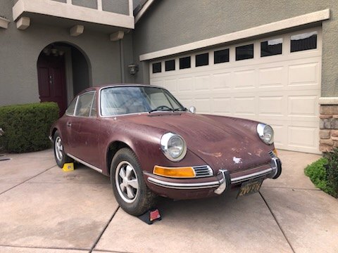 Maroon early Porsche 911 in front of a garage door