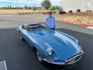 Light blue Jaguar E-Type roadster on a country road