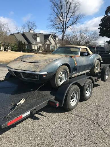 Corvette loaded on a flatbed trailer in a driveway