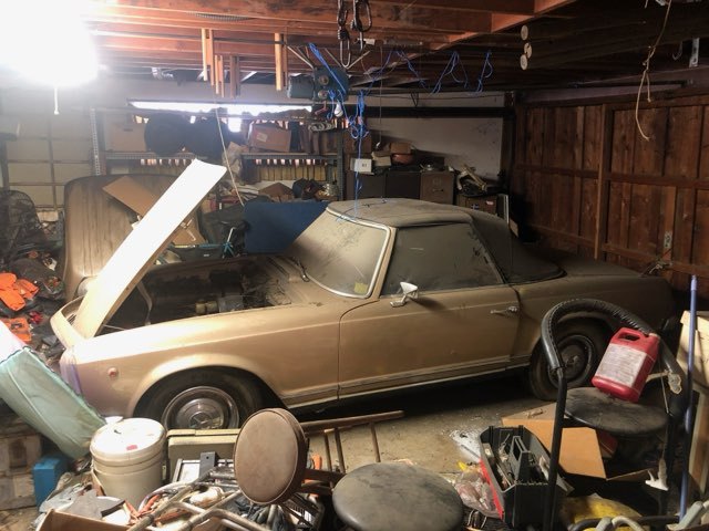Dusty gold Porsche 911 stored in a cluttered garage