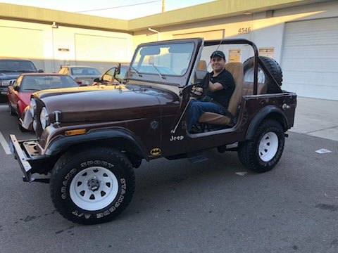 Brown Jeep CJ Scrambler with a driver at the wheel