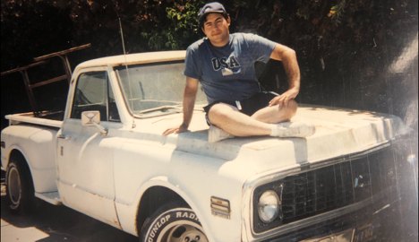 Sitting on the hood of a white 1960s Chevrolet C10 pickup in the early 2000s