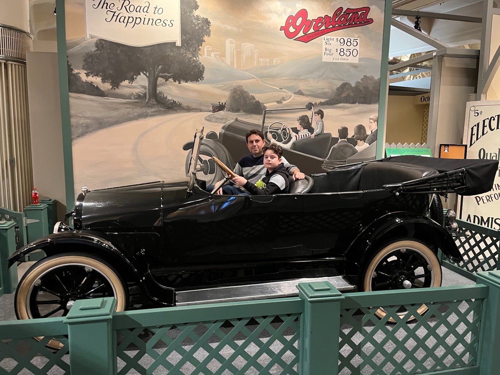 Father and son seated in an antique touring car at the Henry Ford Museum in Detroit